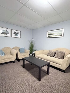 A room with two beige sofas, a dark coffee table, and framed artwork on the walls.