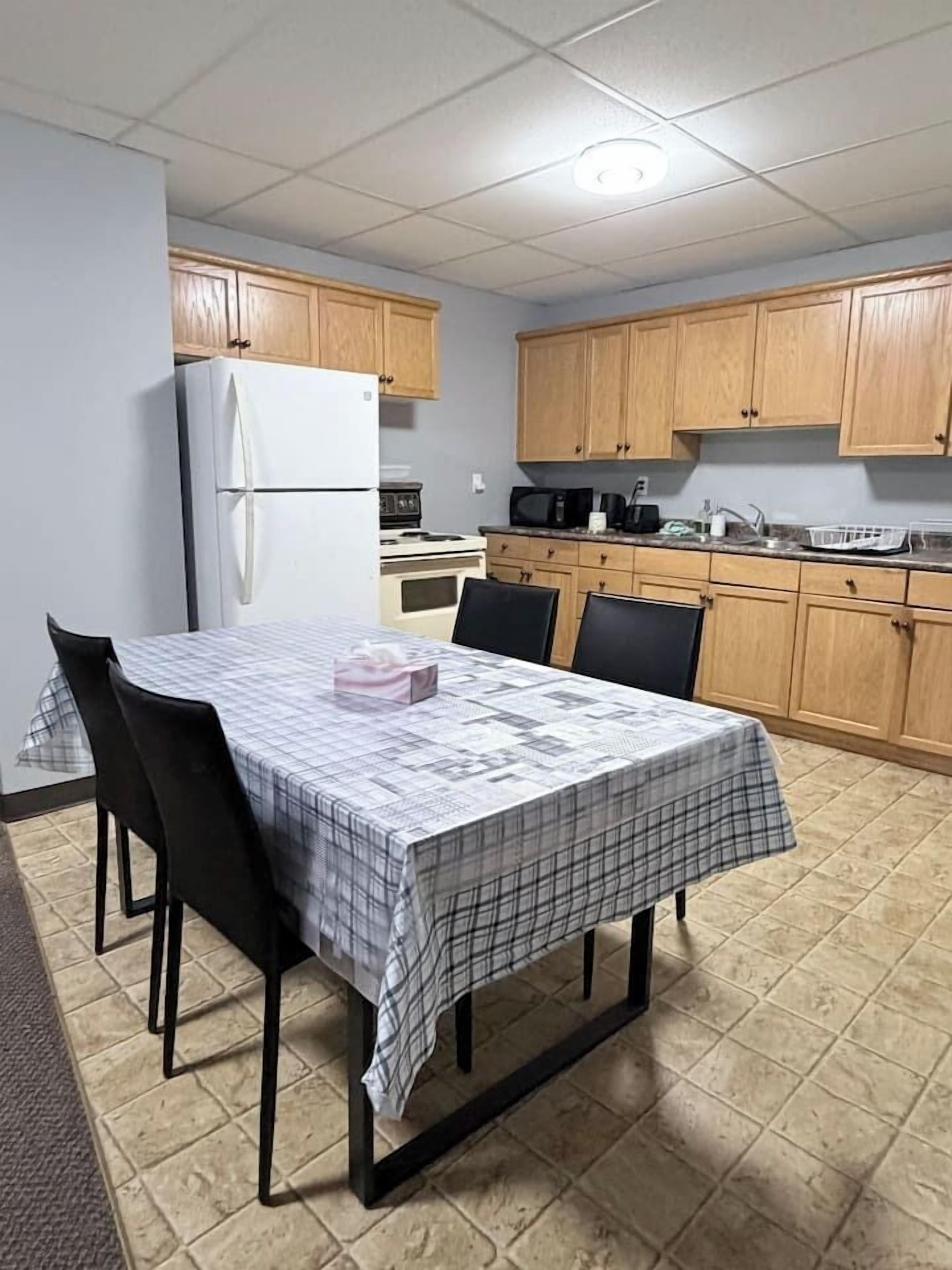 Une cuisine compacte avec des meubles en bois, un réfrigérateur blanc et une table à manger accompagnée de chaises.