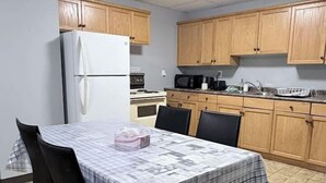 A compact kitchen with wooden cabinets, a white refrigerator, and a dining table set with chairs. - Private 2BR Suite Near Downtown & Hospital (Regina)