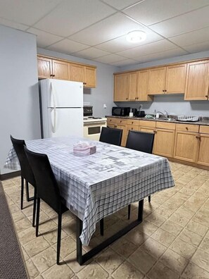 A compact kitchen with wooden cabinets, a white refrigerator, and a dining table set with chairs. - Private 2BR Suite Near Downtown & Hospital (Regina)