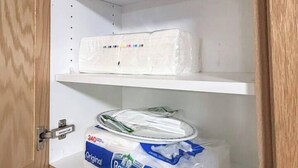 A cabinet with three shelves; the bottom shelf has a package of Royale toilet paper.