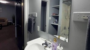 A bathroom with a white sink, a large mirror, and a shower area. - Private 2BR Suite Near Downtown & Hospital (Regina)