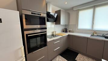 A modern kitchen with built-in appliances, a window, and a clean design.