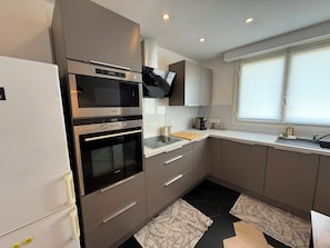 A modern kitchen with built-in appliances, a window, and a clean design.