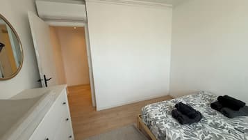 Un dormitorio con cama, cómoda, espejo y puerta que da a otra habitación.