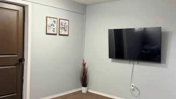 Une pièce dotée d’un téléviseur à écran plat fixé au mur, d’une porte et d’une petite table.