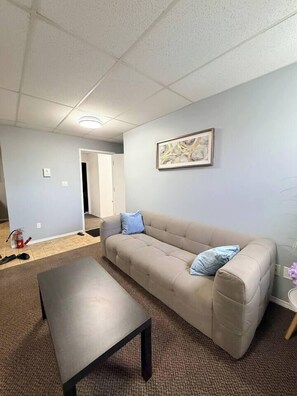 A living room with a beige sofa, a dark coffee table, and a framed picture on the wall.