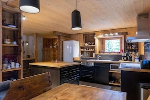 A rustic kitchen with wooden cabinets, a white refrigerator, and a wooden dining table. - Chalet, 150m from ski slopes, 3rd floor, view panoramic, terrace, fireplace or stove, 250m² (Champagny-en-Vanoise)