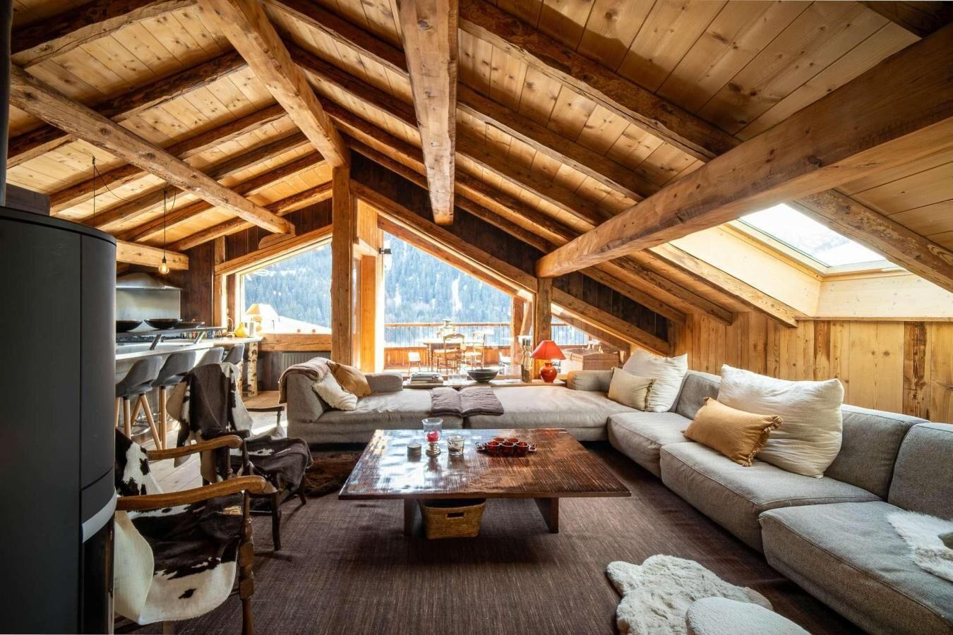 A cozy loft-style room with a wooden ceiling, a sofa, a coffee table, and a view of the outdoors.