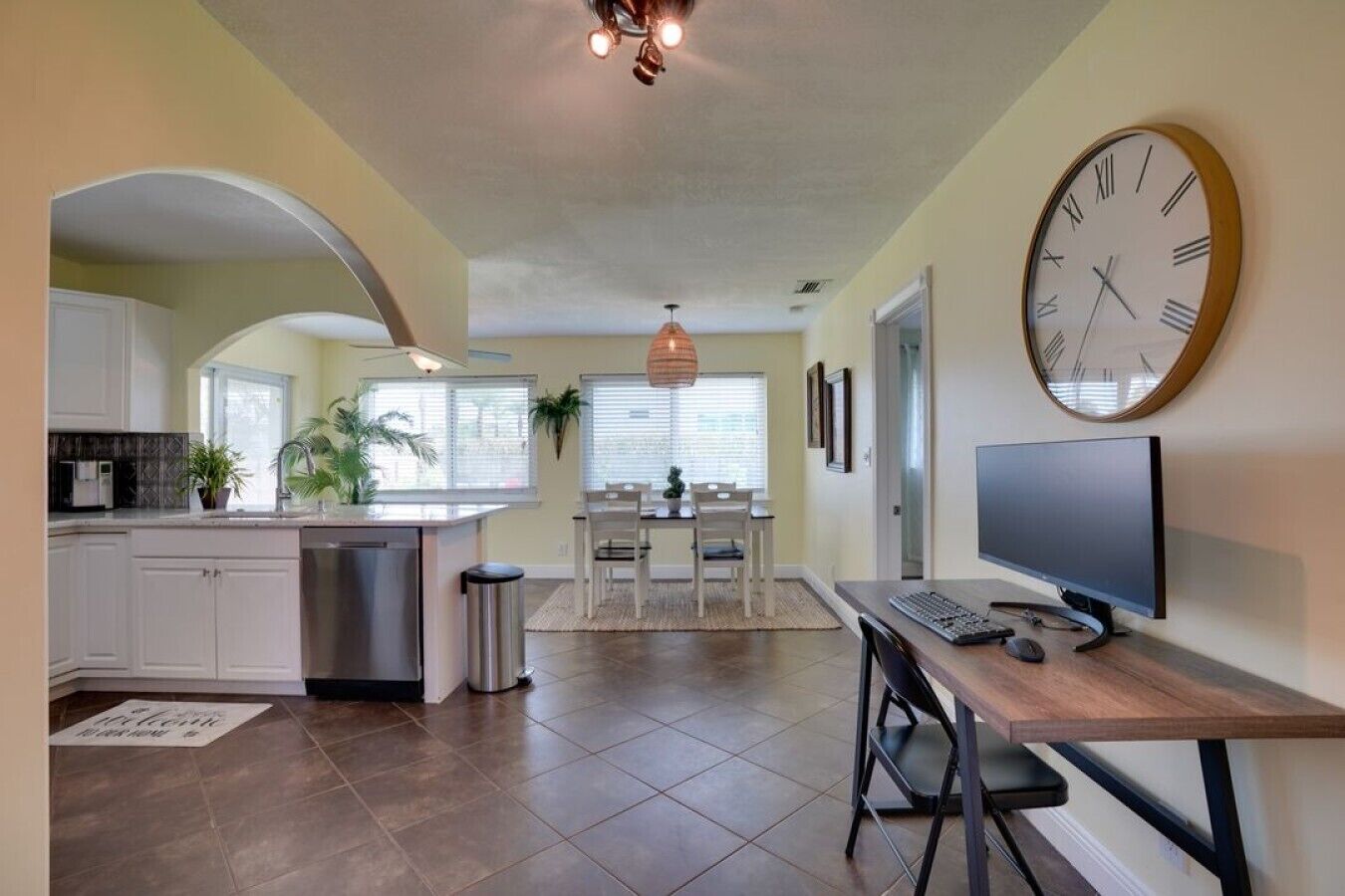A modern kitchen with a dining area, a TV, and a clock on the wall.