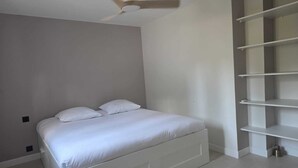 Ein Schlafzimmer mit einem Bett, einem Deckenventilator und eingebauten Regalen.