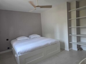 Ein Schlafzimmer mit einem Bett, einem Deckenventilator und eingebauten Regalen.