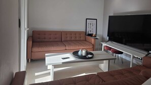Ein Wohnzimmer mit einer Couch, einem Couchtisch, einem Fernseher und einem Deckenventilator.