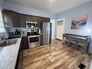 A modern kitchen with stainless steel appliances, a granite countertop, and a wooden floor. - The Market House exudes charm and comfort.  It has a large open concept and all the amenities of home. (Ashland)
