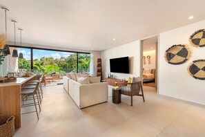 Een moderne woonkamer met een grote televisie, een bank, een eethoek en uitzicht op groen.