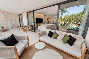 Een moderne woonkamer met een bank, stoelen, een salontafel en een televisie.