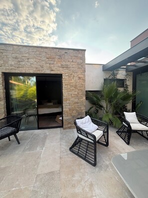 An outdoor patio area with stone walls, a glass door leading to a room, and wicker furniture. - Exceptional Villa, Arcachon Bay, Infinity Pool (Le Teich)