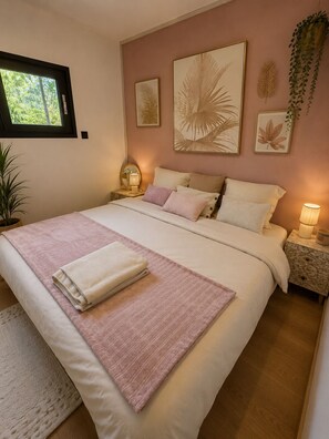 Een slaapkamer met een bed, nachtkastjes, een raam en wanddecoratie.