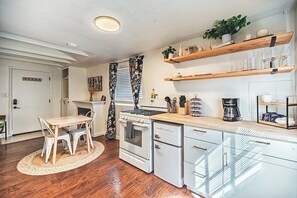 Eine kleine Küche mit weißen Schränken, einer Holz Arbeitsplatte und einem Essbereich mit Tisch und Stühlen.