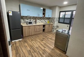 Cocina compacta con armarios azul claro, microondas, fregadero y lavavajillas de acero inoxidable.