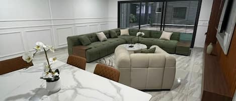 A modern living room with a sectional sofa, a marble coffee table, and a dining area with a white table.