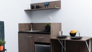 A compact kitchen with a built-in dishwasher, a wooden countertop, and a small shelf above the sink.