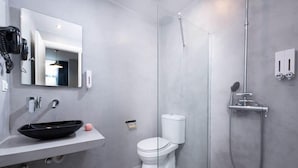 A modern bathroom with a glass shower enclosure, a white toilet, and a black vessel sink.