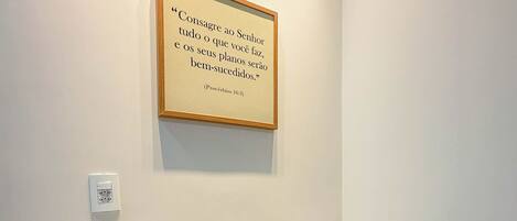 A hotel bathroom with a granite countertop, a framed quote on the wall, and a mirror.