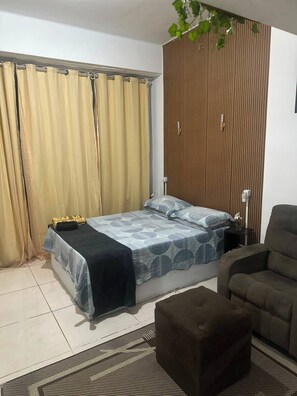 A bedroom with a bed, a chair, a small table, and a wooden partition. - Lapa Heart Studio (Rio de Janeiro)
