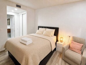 Ein Schlafzimmer mit einem Bett, Nachttischen, einem Sessel und einem Beistelltisch mit Lampe.