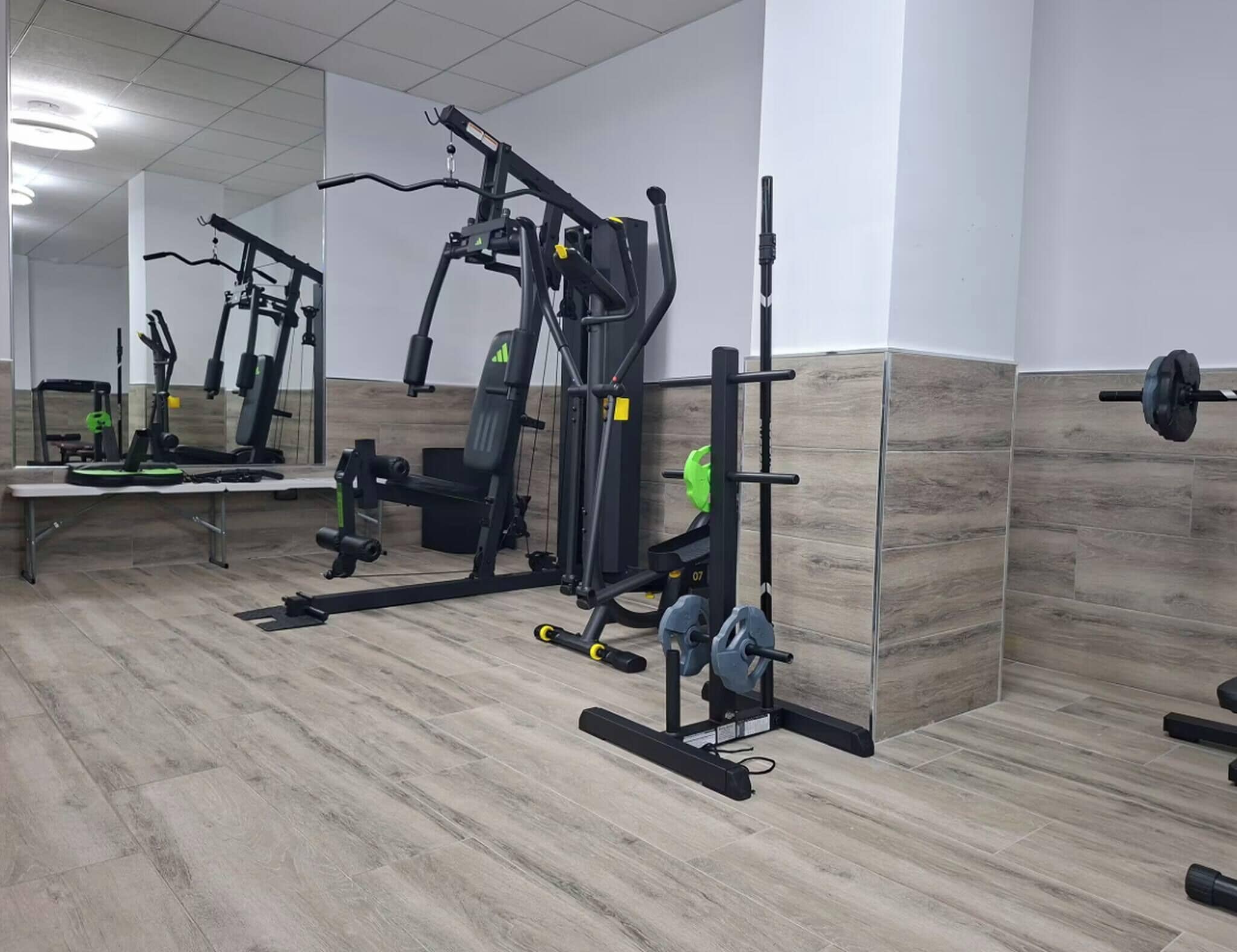 A gym with various exercise equipment, including a bench press, squat rack, and weight bench.