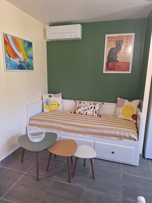 A single-bed room with a green wall, a bed with striped bedding, a small table with a chair, and a poster on the wall. - The Agapanthus of the Albères (VILLELONGUE DELS MONTS)