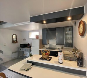 Uma cozinha moderna com armários cinzentos, micro-ondas, pia e uma fruteira sobre o balcão.