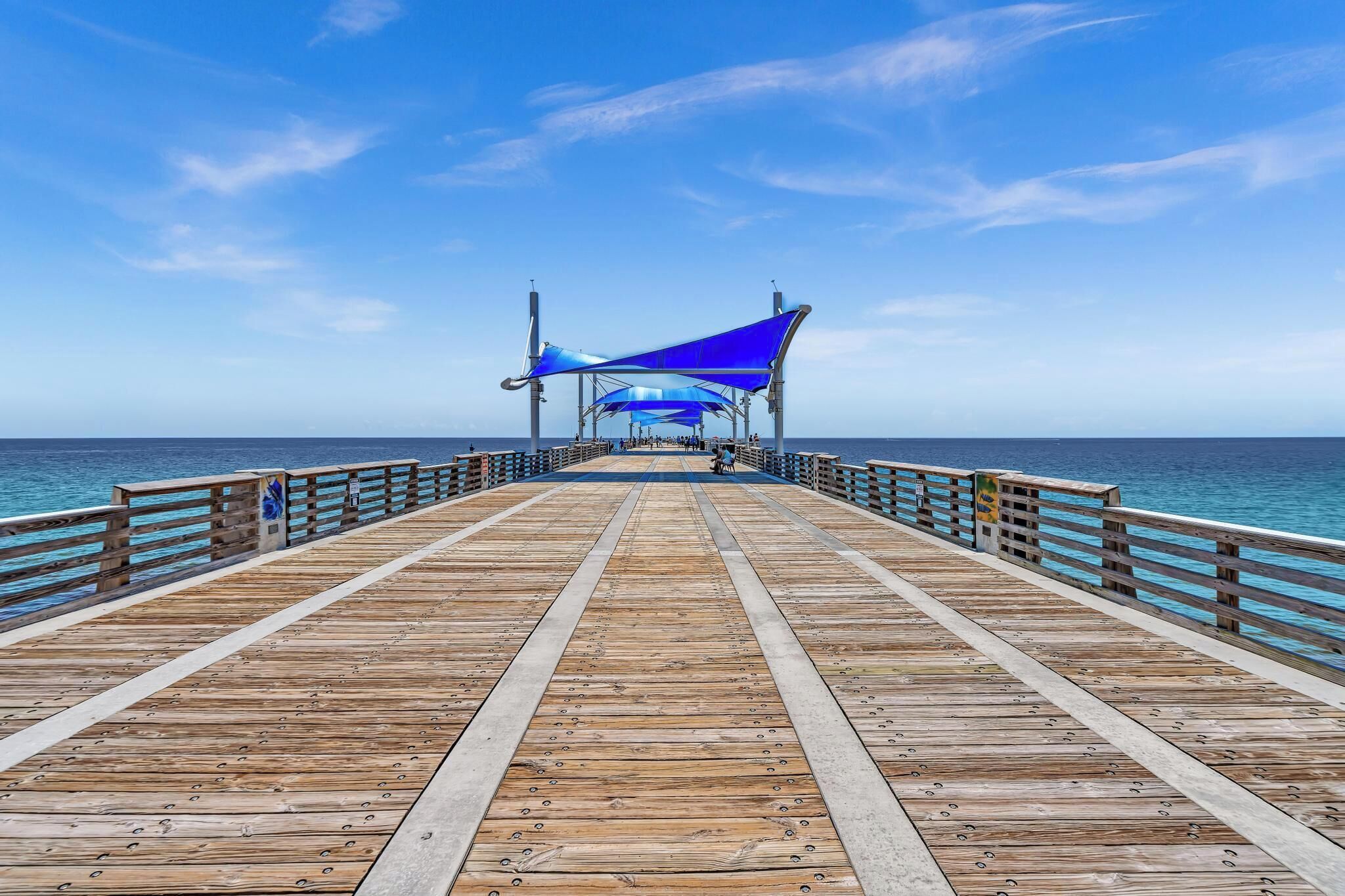 Un muelle de madera que se adentra en el mar bajo un cielo despejado.
