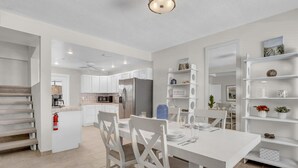 A modern kitchen with white cabinetry, a dining table set for four, and a built-in shelving unit. - LaPlaya Pompano Private Beach + Pool (Pompano Beach)