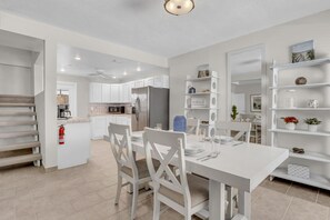 A modern kitchen with white cabinetry, a dining table set for four, and a built-in shelving unit. - LaPlaya Pompano Private Beach + Pool (Pompano Beach)