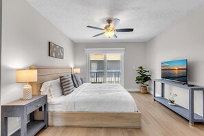 A bedroom with a bed, bedside tables, a ceiling fan, a TV, a balcony, and a view of the sea. - LaPlaya Pompano Private Beach + Pool (Pompano Beach)
