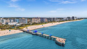 A coastal cityscape with a pier extending into the sea, surrounded by high-rise buildings and a sandy beach. - LaPlaya Pompano Private Beach + Pool (Pompano Beach)