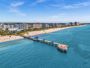 A coastal cityscape with a pier extending into the sea, surrounded by high-rise buildings and a sandy beach. - LaPlaya Pompano Private Beach + Pool (Pompano Beach)