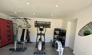 A home gym with an elliptical, a stationary bike, and a fan. - The Birds of Paradise (VILLELONGUE DELS MONTS)