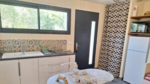 Cozinha compacta com área de refeições, pia, geladeira e janela com vista para o verde.