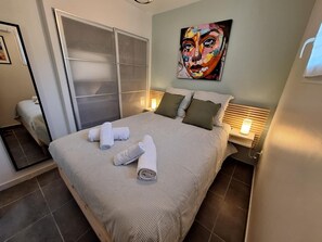 A hotel room with a bed, a painting on the wall, and a window with blinds. - The Birds of Paradise (VILLELONGUE DELS MONTS)