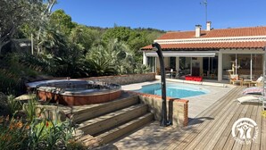 Uma área de piscina com hidromassagem, deck de madeira e uma casa com telhado telhado.