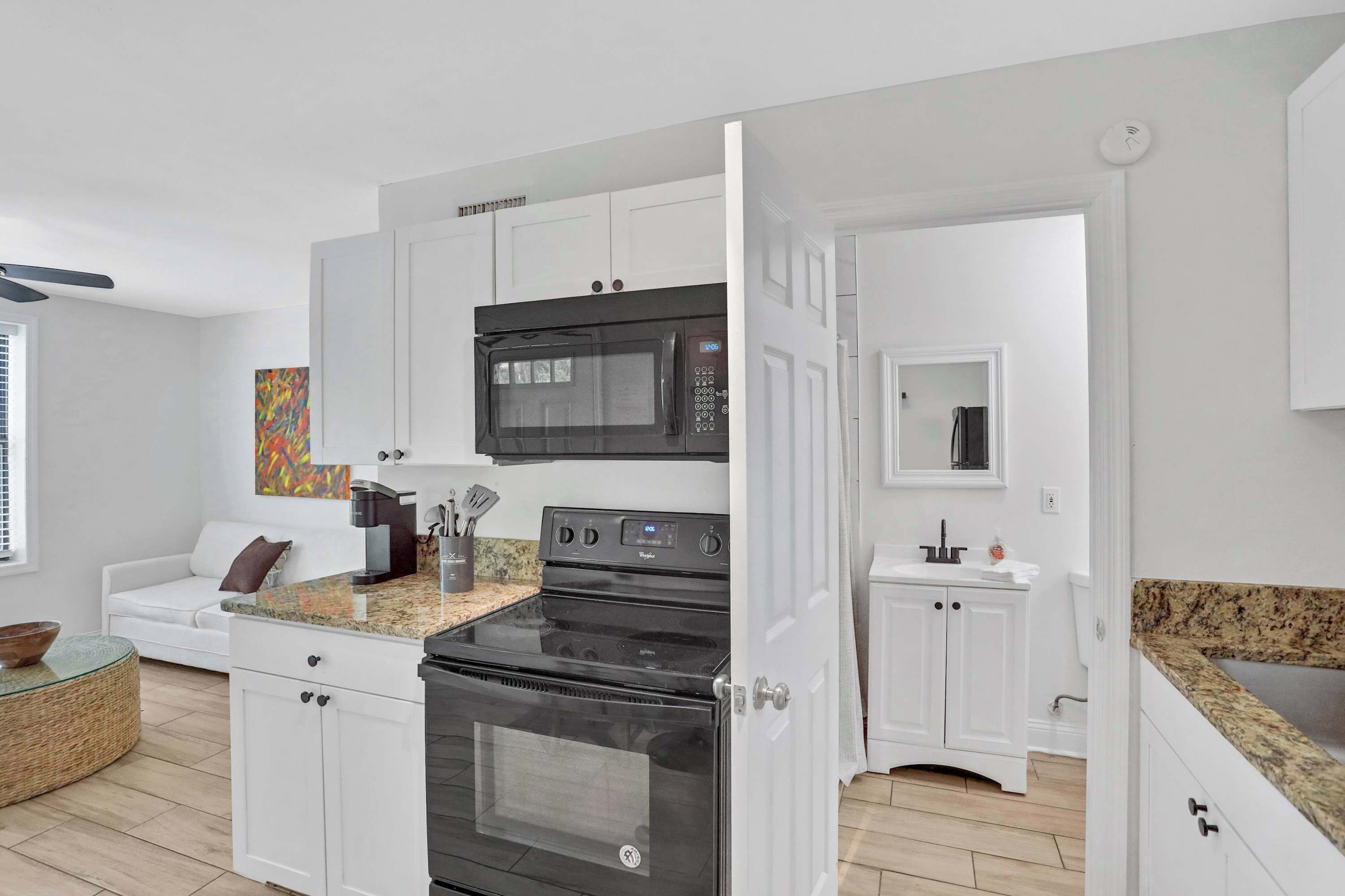 A modern kitchen with white cabinetry, a black stove, a microwave, and a built-in oven.
