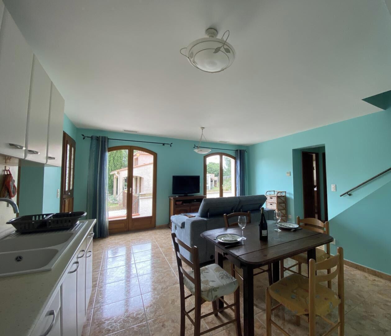 A spacious kitchen with a dining area, a television, and a sofa.
