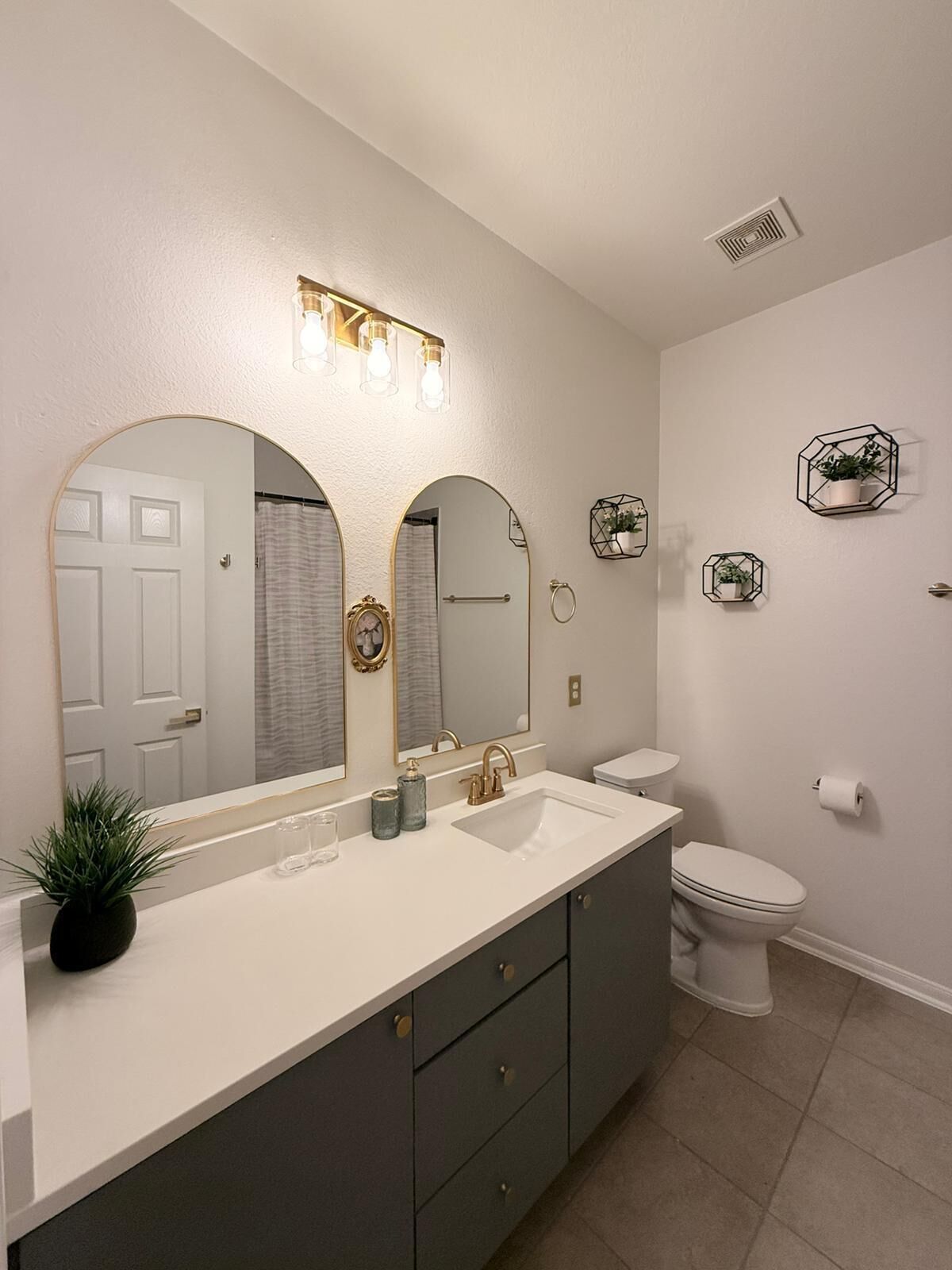 A bathroom with a double sink vanity, a toilet, and a shower curtain.