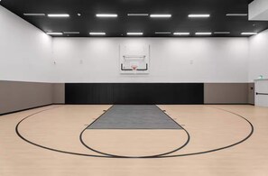 Ein Basketballplatz mit Korb, gepolsterten schwarzen Wänden und Deckenleuchten.