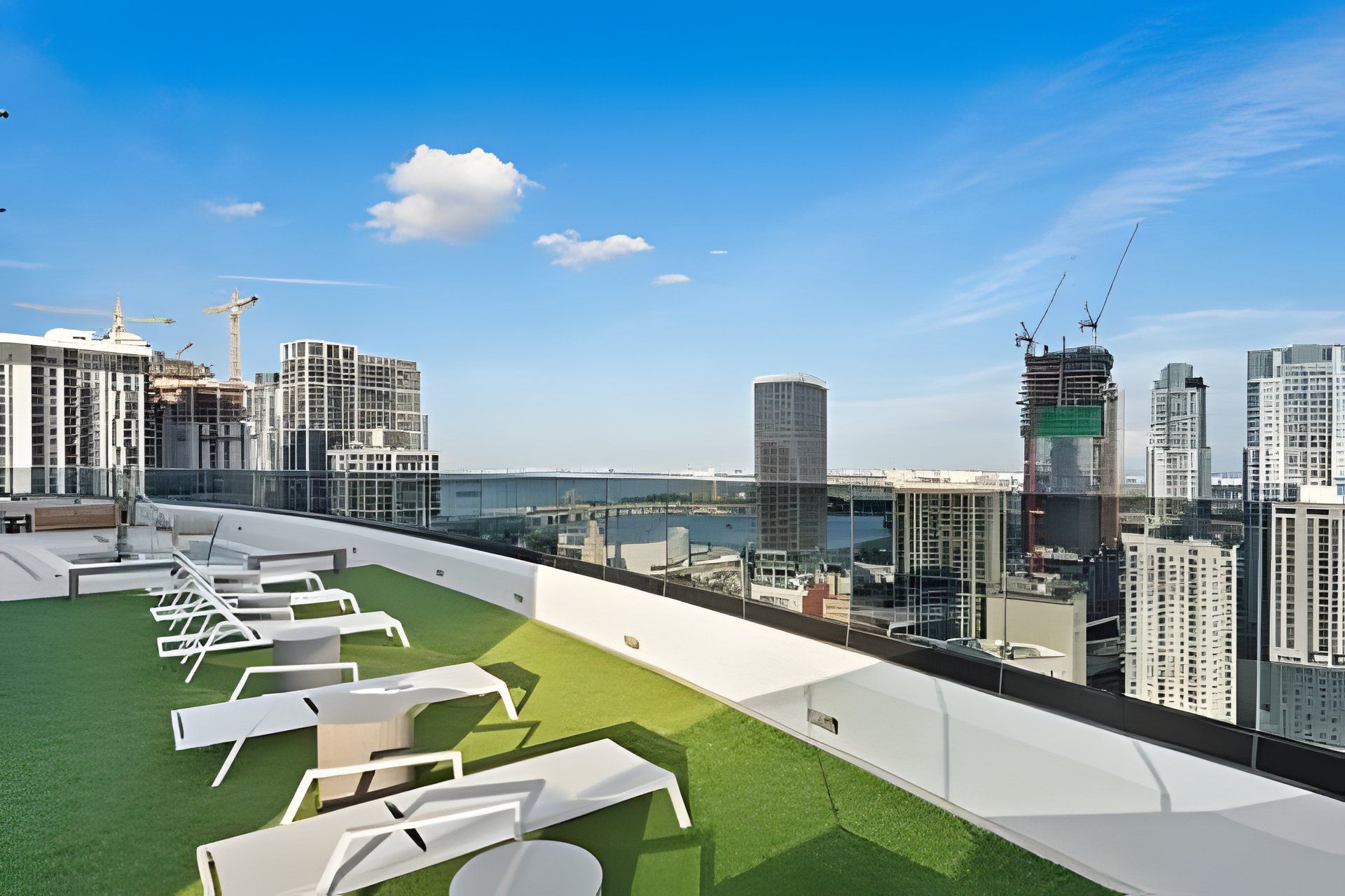 A rooftop terrace with lounge chairs and a view of a cityscape.