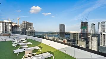 A rooftop terrace with lounge chairs and a view of a cityscape.