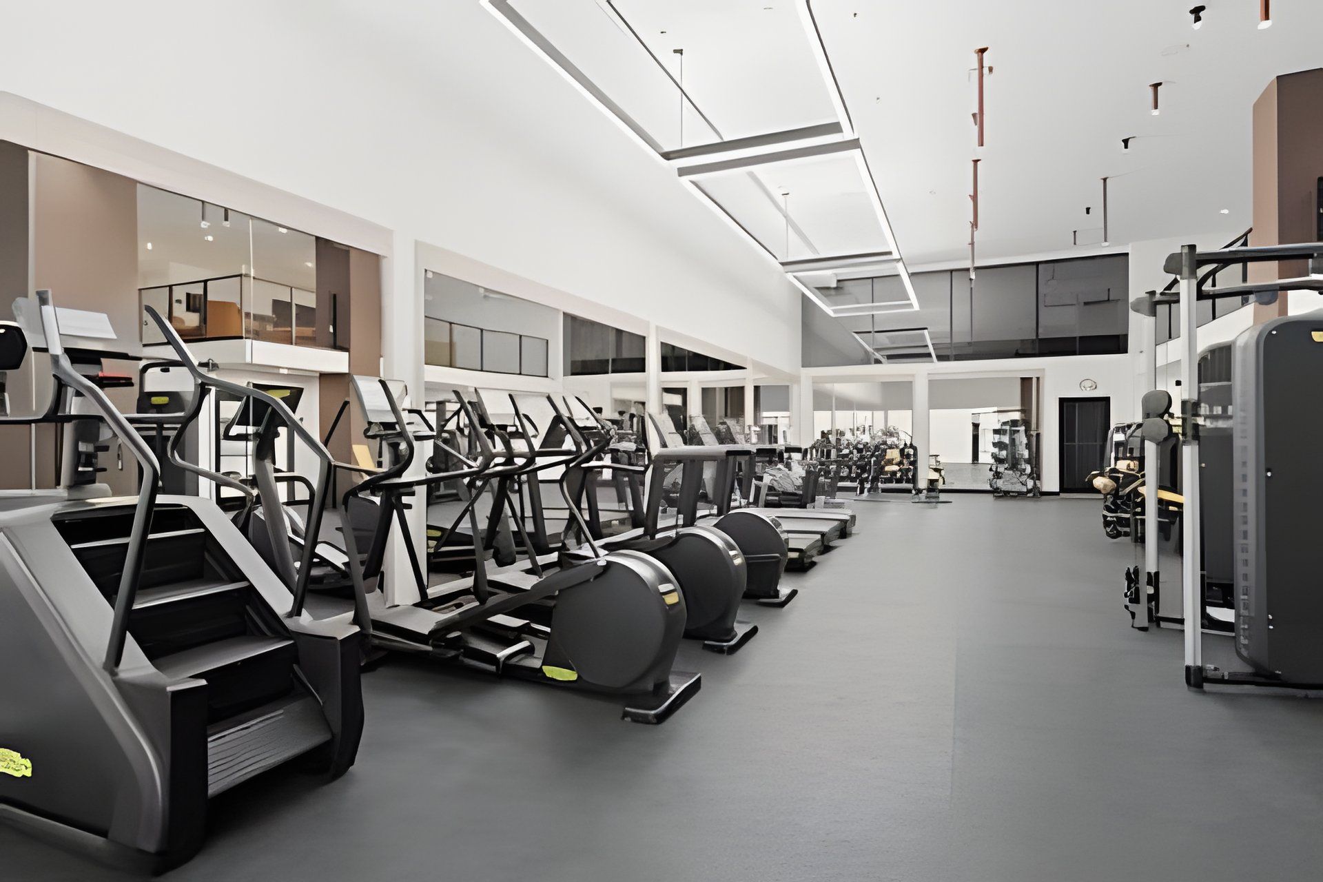 Ein Fitnessstudio mit Laufbändern, Crosstrainern und Gewichten.